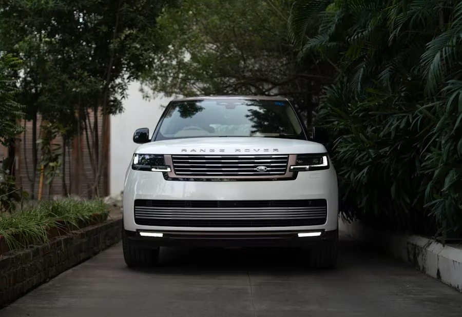 White Range Rover on a tree-lined driveway.