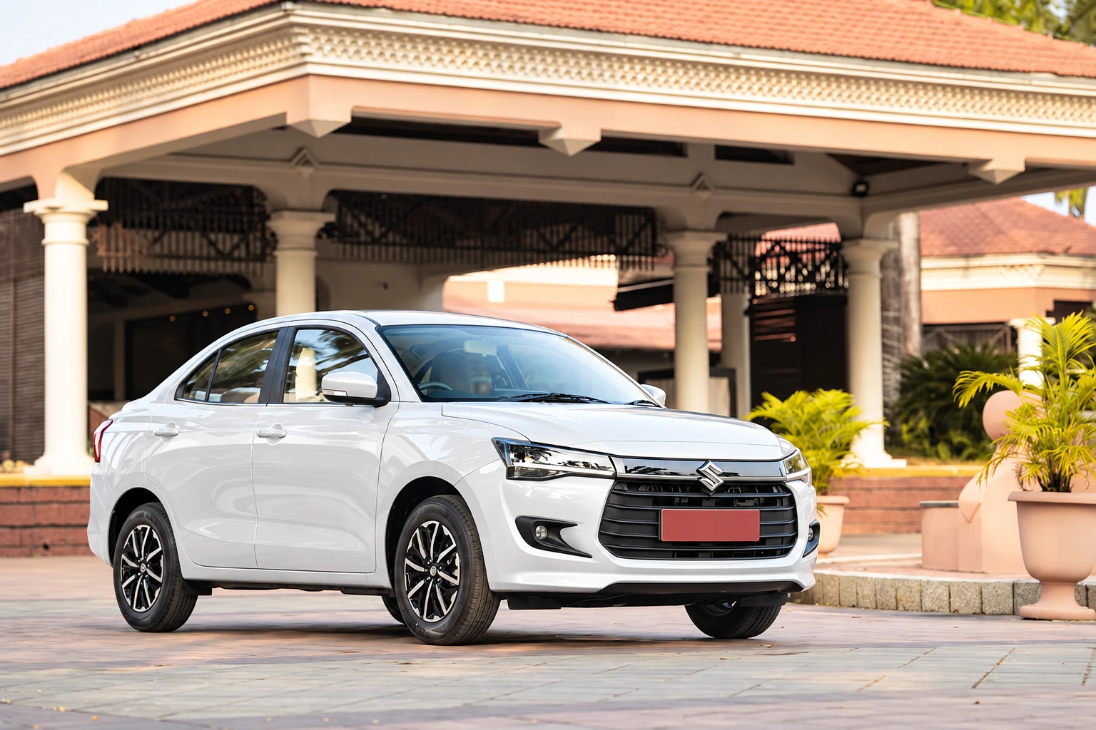 White Maruti Suzuki Dzire outside a building entrance.