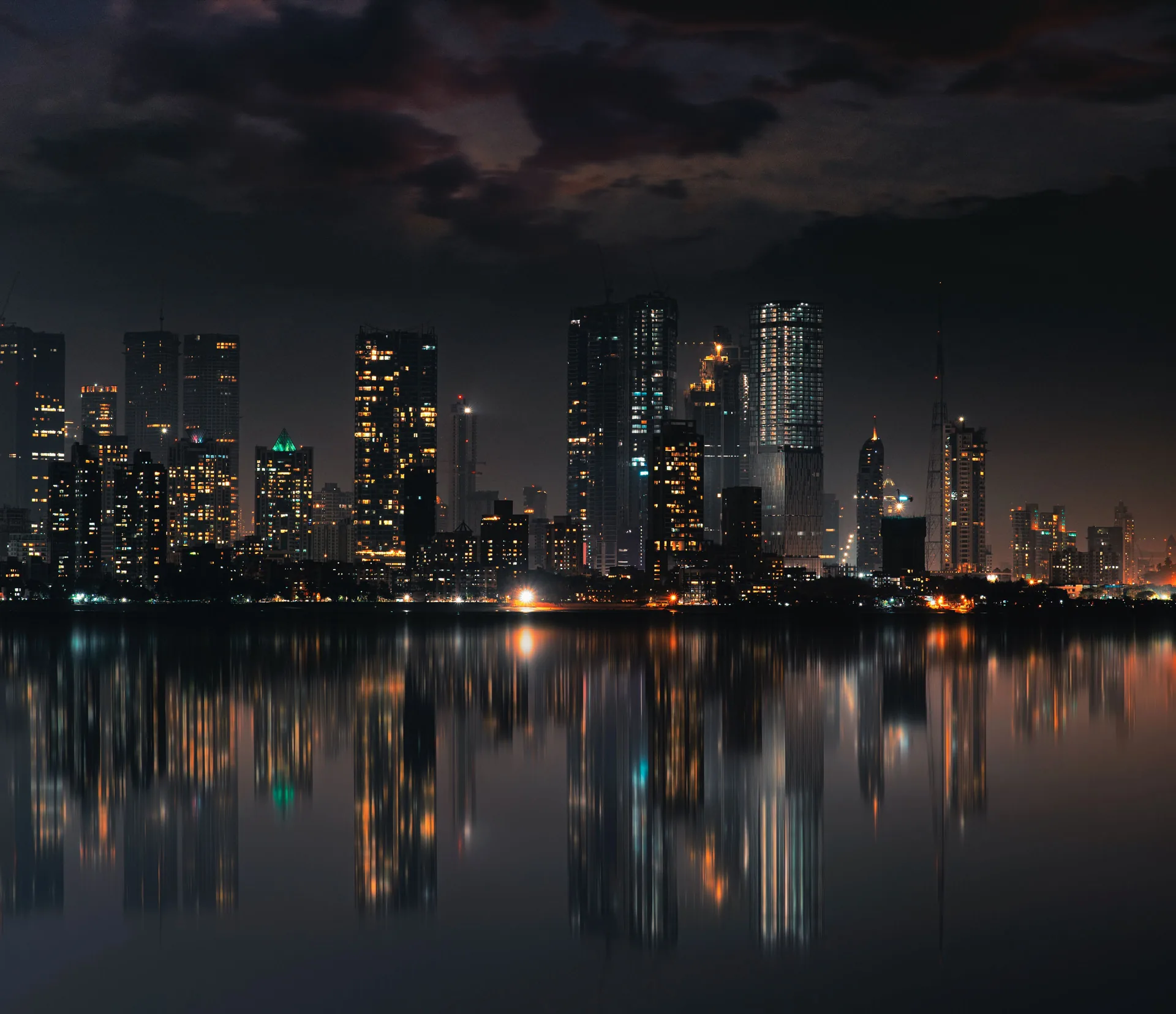 A city skyline at night reflected in still water.