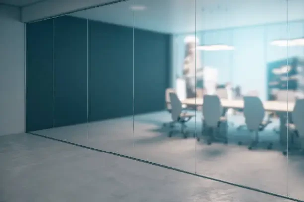 A glass-walled office meeting room with a table and chairs.