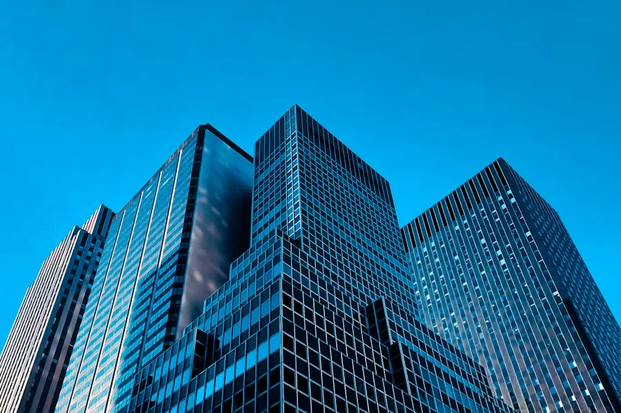 Glass office towers viewed from below against a blue sky.