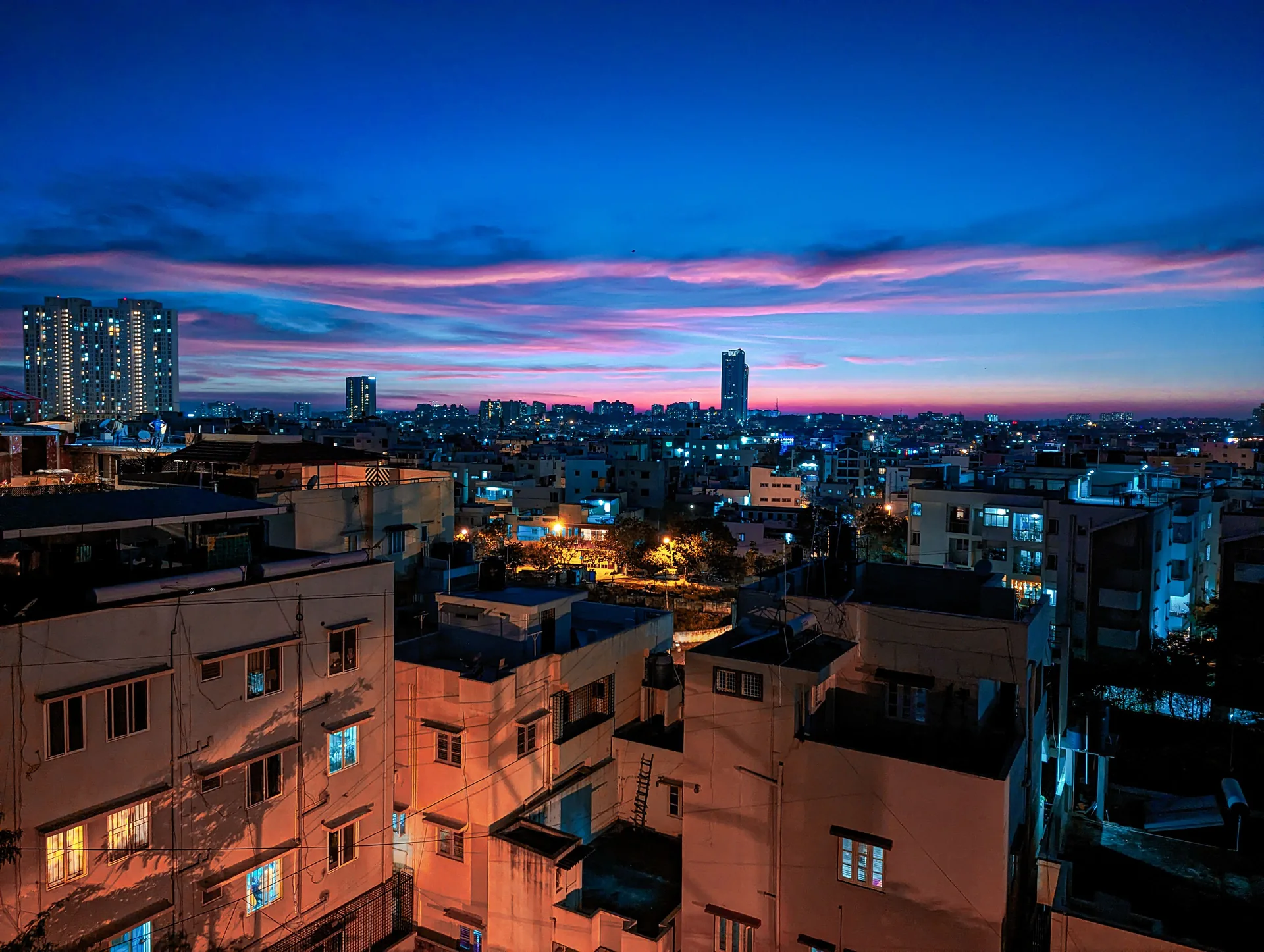 An Indian city at dusk, lit buildings under a deep blue and pink sky.