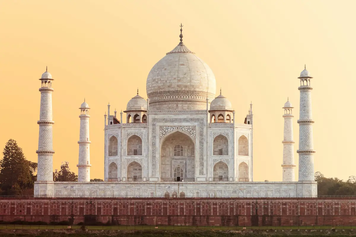 The Taj Mahal at golden hour under a warm, hazy sky.