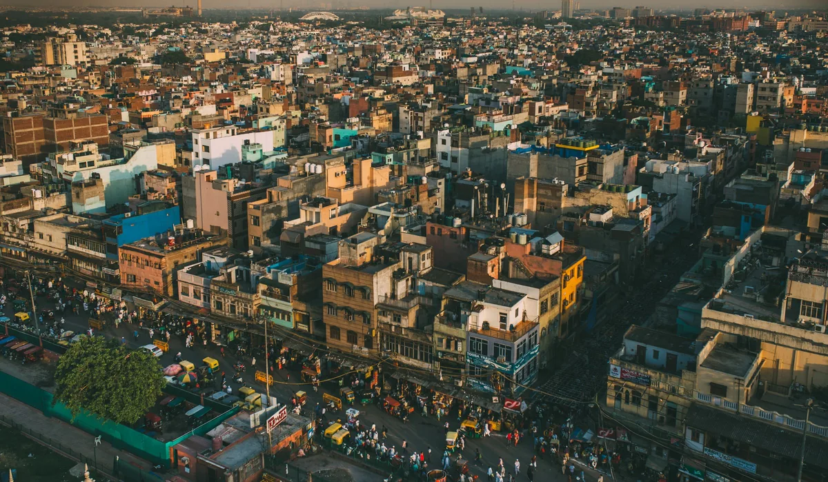 Dense rooftops of an Indian city seen from above in warm afternoon light.