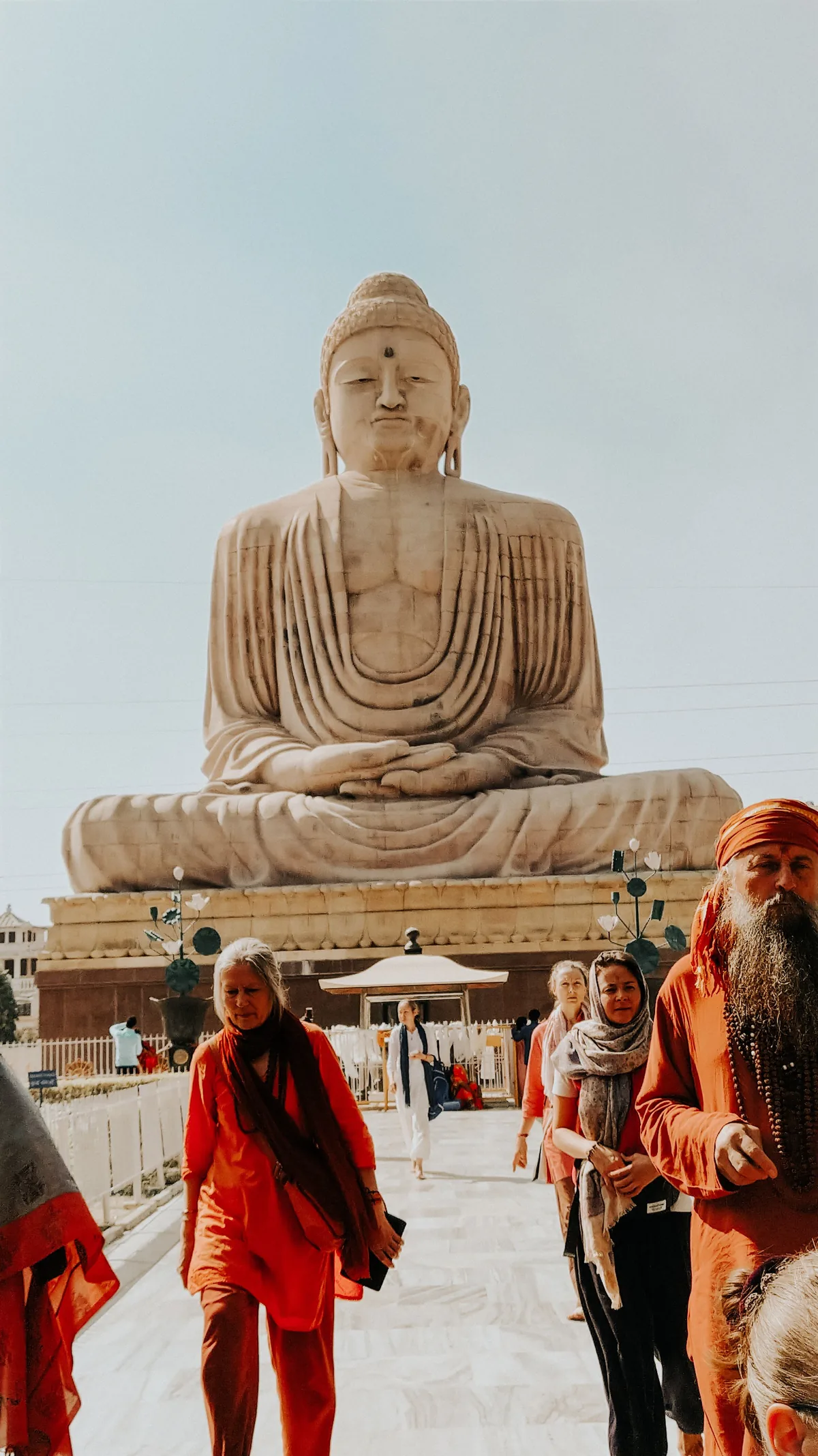 A large seated Buddha statue on the water at Hyderabad, with visitors at its base.