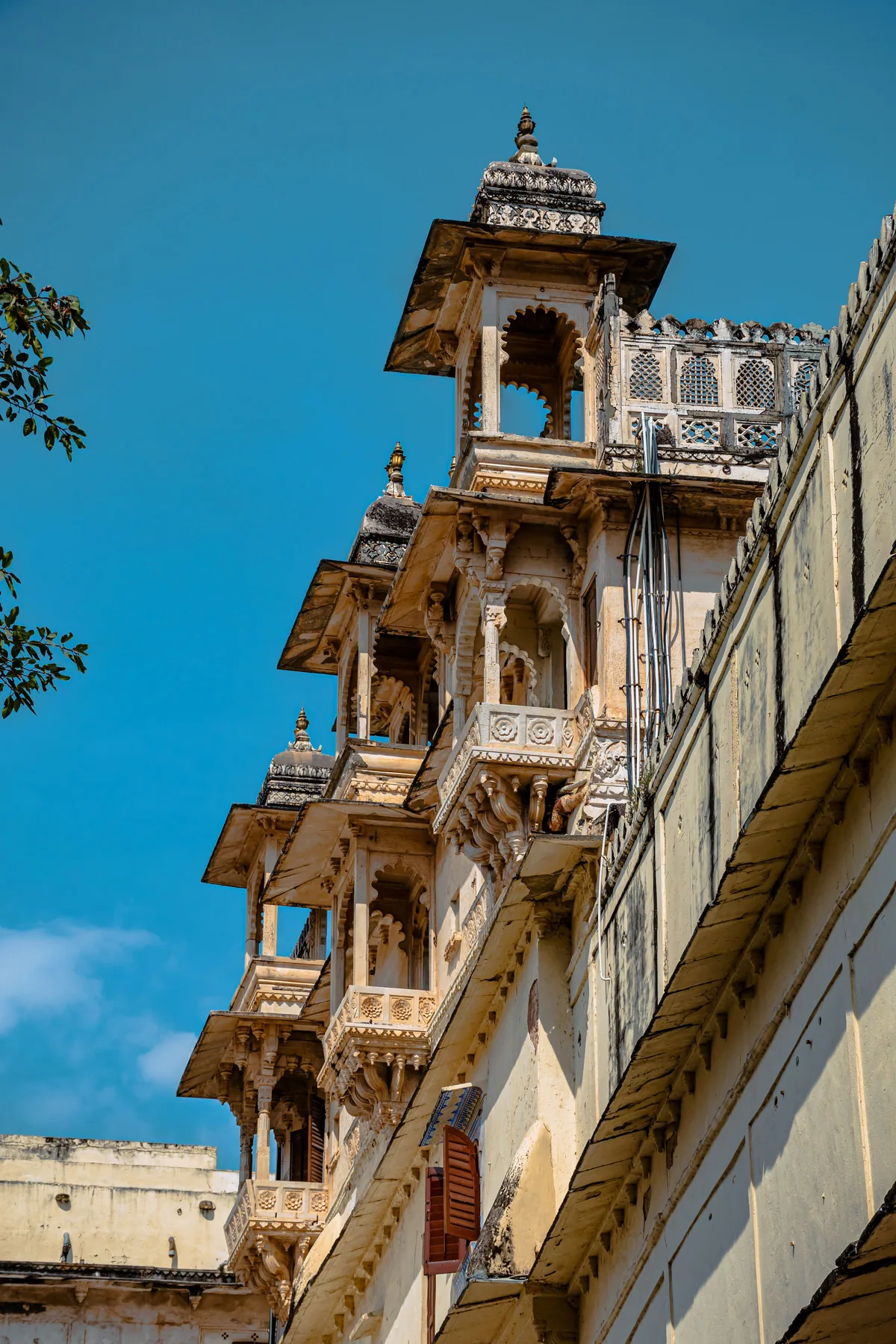 Carved Rajasthani palace architecture in Udaipur against a clear sky.