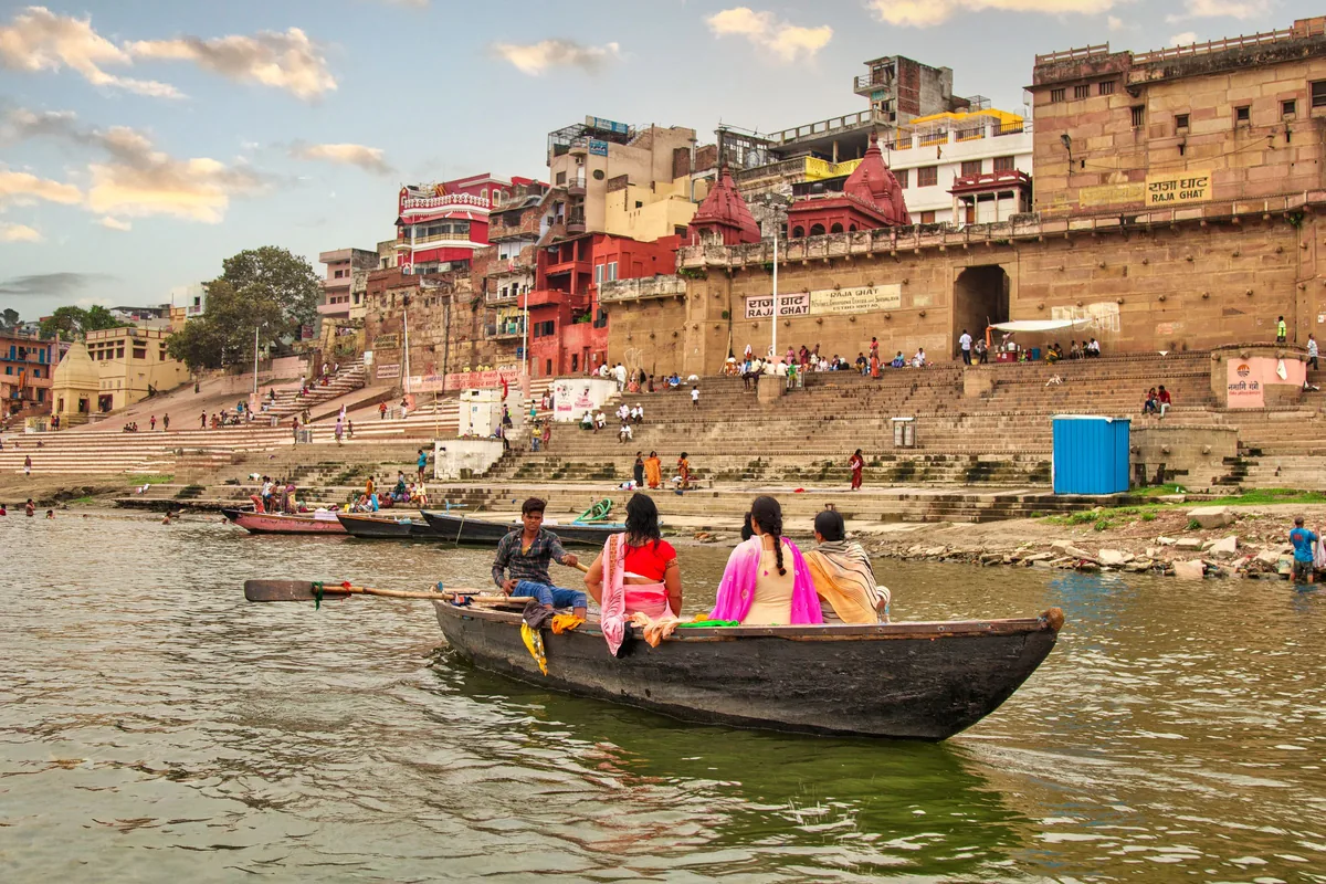 The ghats at Varanasi seen from the river, with a boat in the foreground.