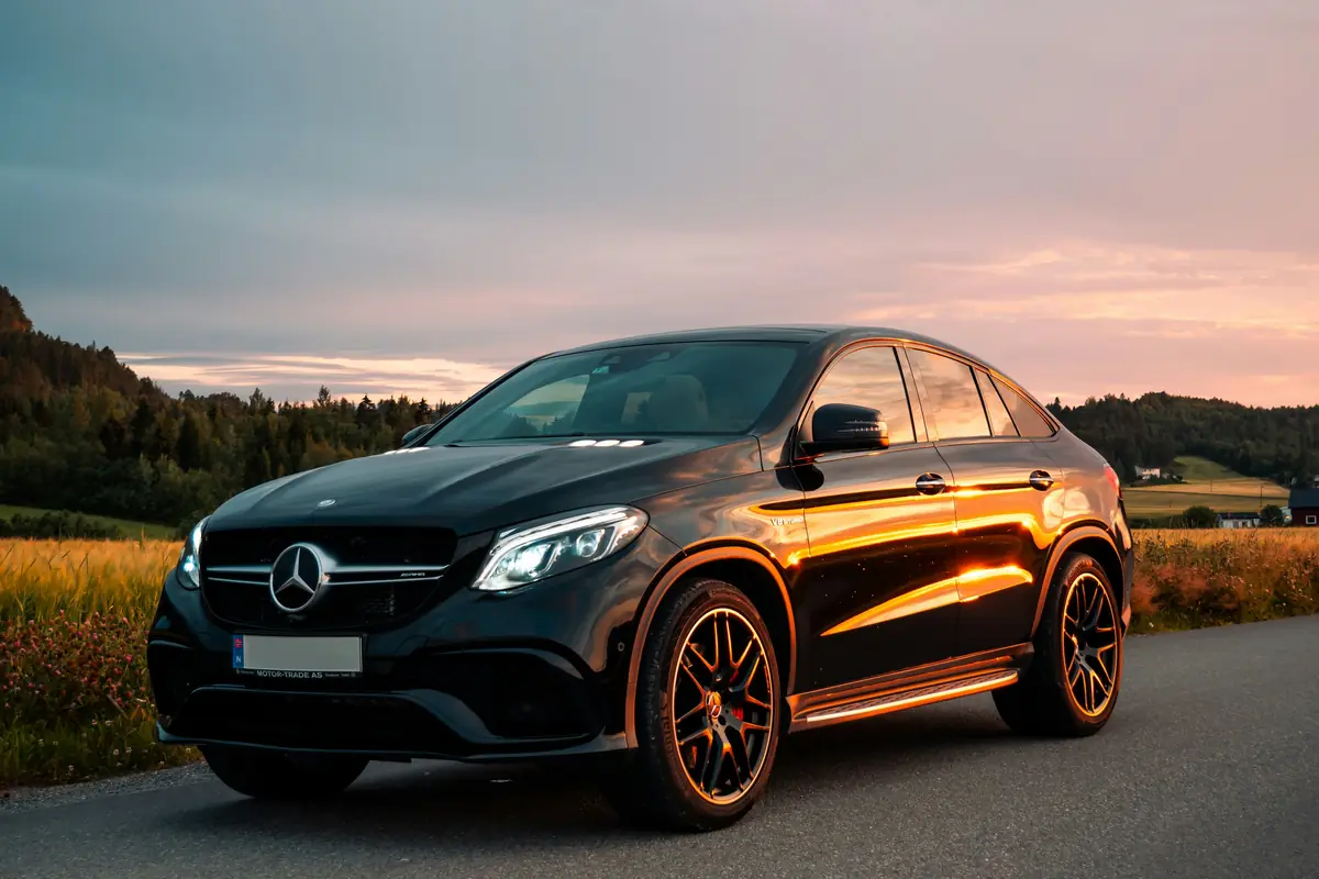 A dark executive saloon parked on an open road under a wide, muted sky.