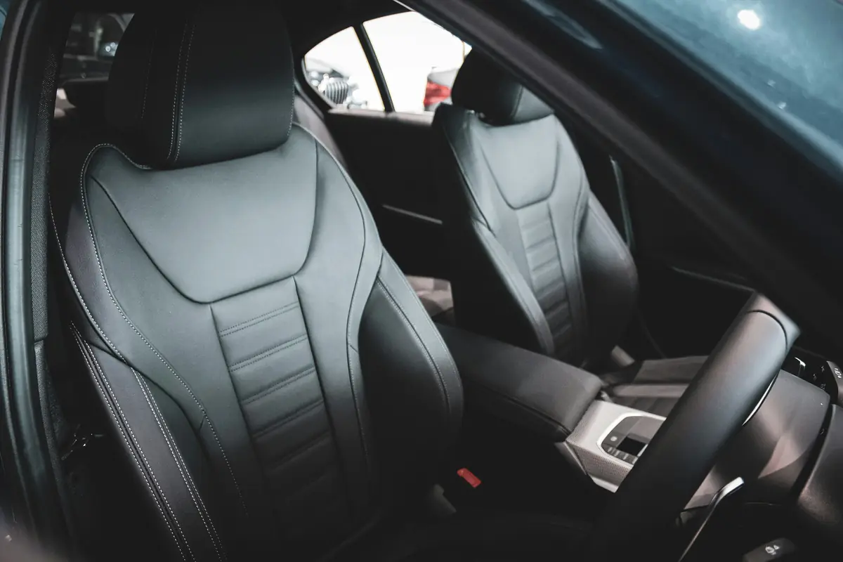A dark leather car interior, front and rear seats in low light.