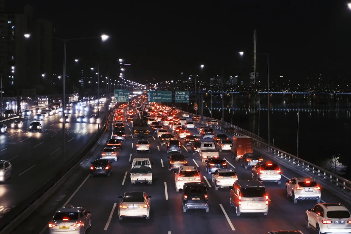 Dense night traffic on a multi-lane urban expressway, seen from above the carriageway.