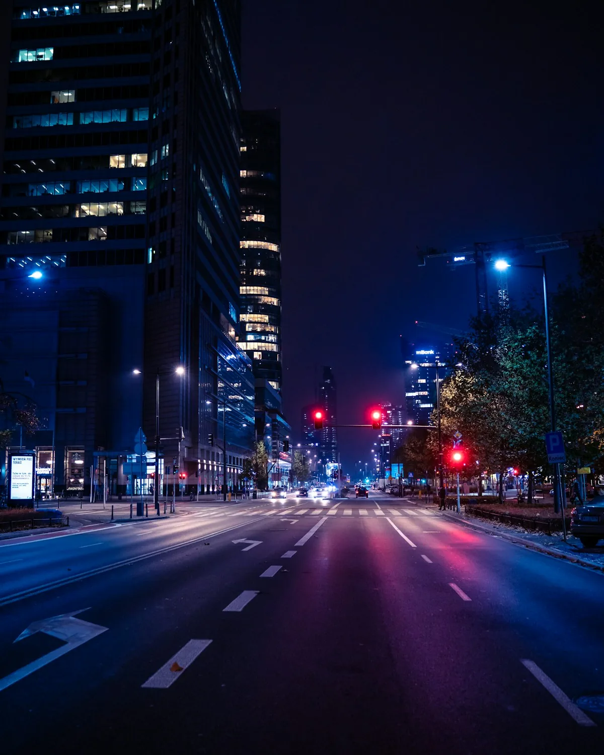 An empty city street at blue hour, signals lit, buildings rising on both sides.
